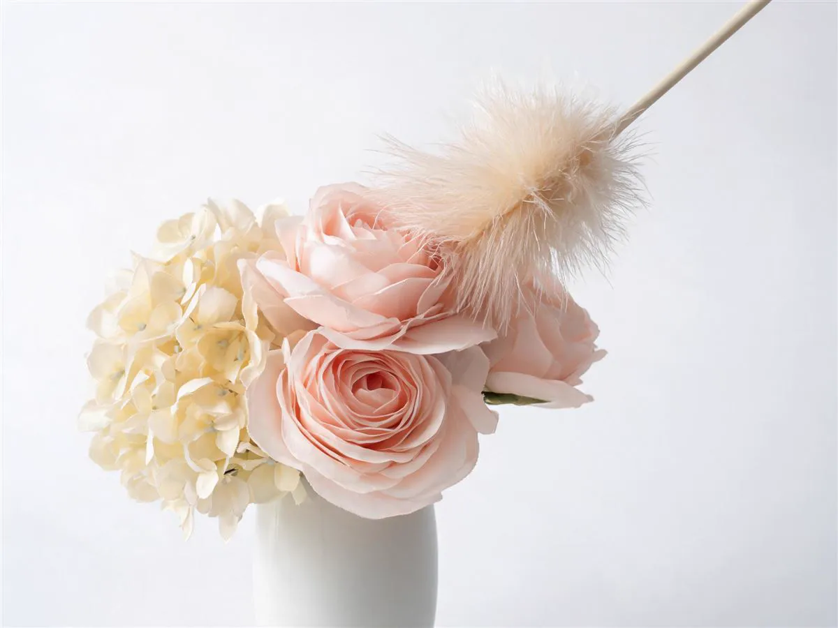 Gently dusting silk rose and hydrangea arrangement with a feather duster